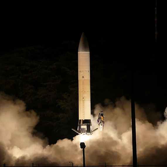 A rocket about to take off during the night. Smoke fills the bottom of the photo as the rocket prepares for take-off.
