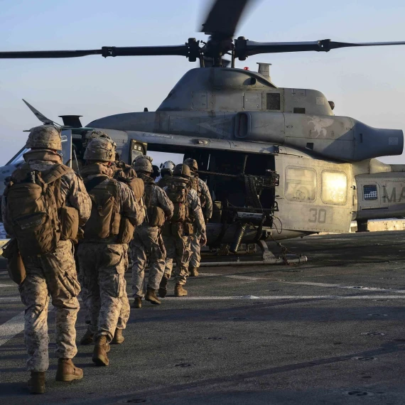 U.S. marines loading onto an AH-1Z Viper attack helicopter that sits on the flight deck aboard the amphibious dock landing ship USS Pearl Harbor (LSD 52).